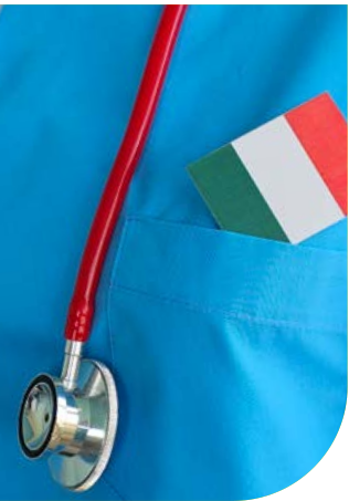 Stetoscopio rosso appoggiato su una casacca sanitaria azzurra, con una piccola bandiera italiana infilata nel taschino.