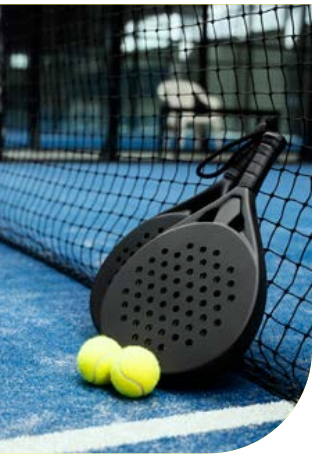 Racchette da padel e palline appoggiate alla rete di un campo da padel